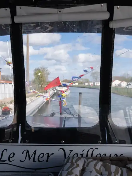 Vue depuis un bateau Le Mer Veilleux du port de plaisance d'Aire-sur-la-Lys avec drapeaux colorés et bâtiments