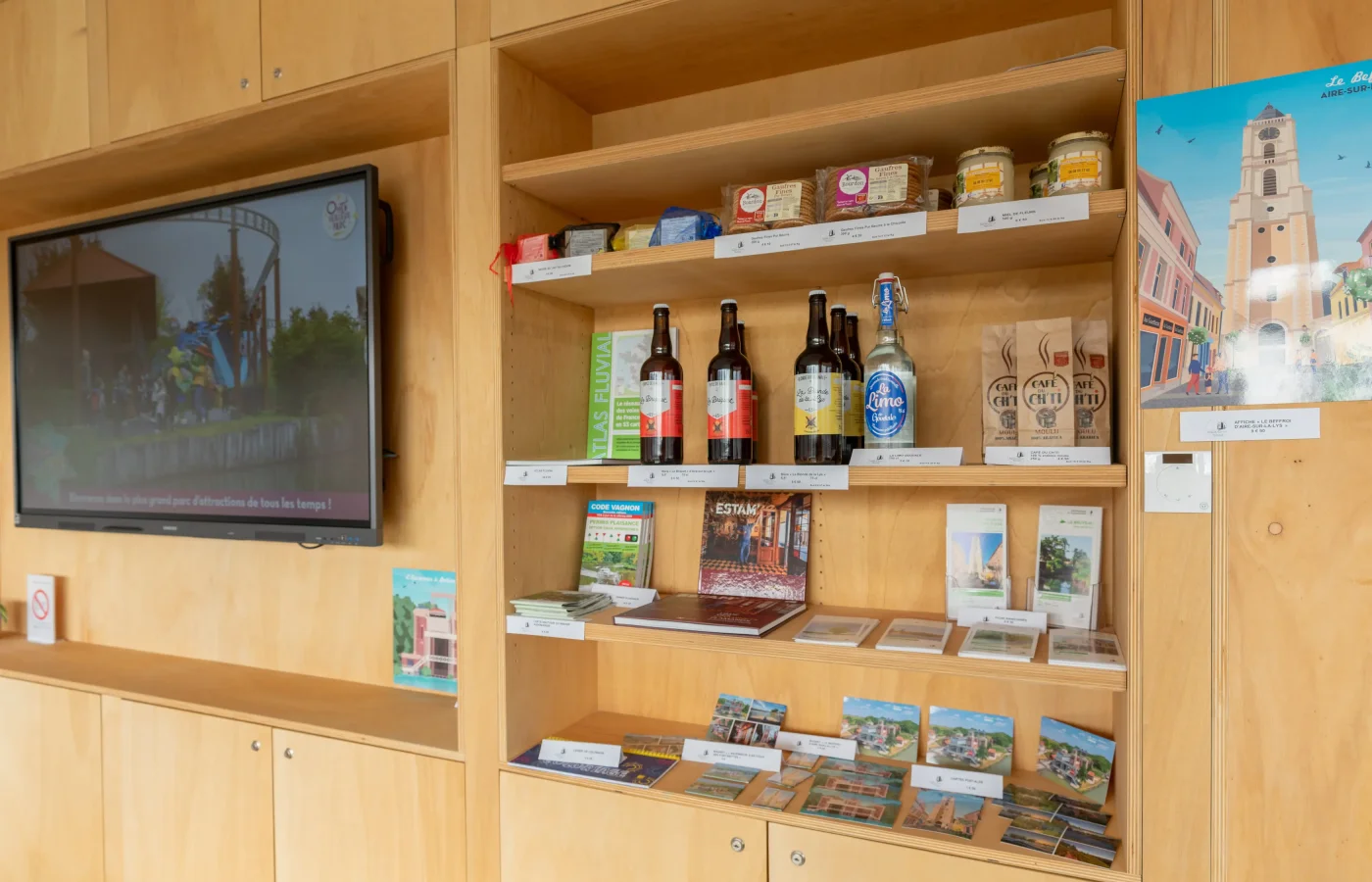 Vitrine en bois exposant bières locales, souvenirs et guides touristiques d'Aire-sur-la-Lys