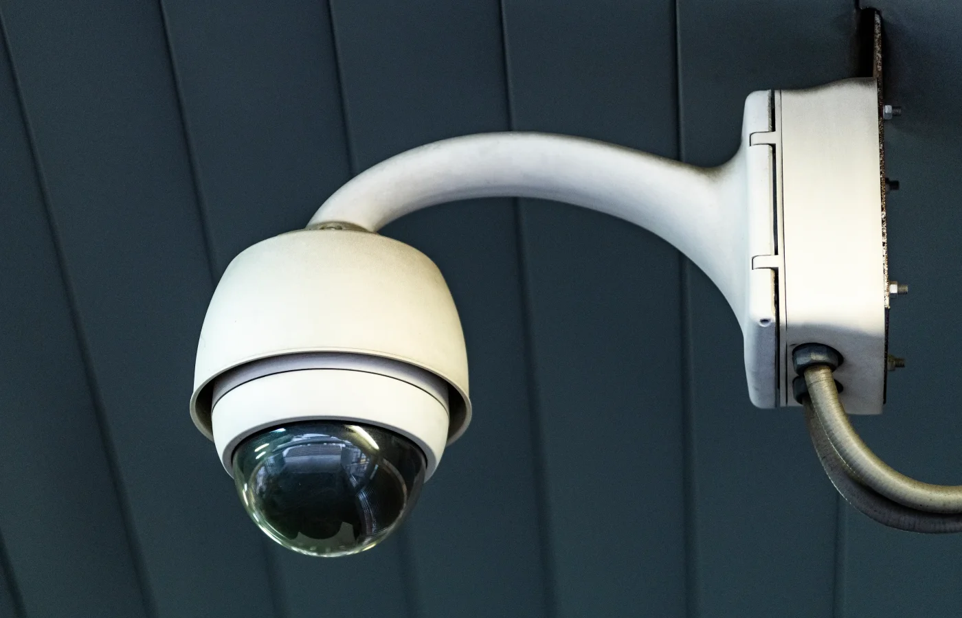 Caméra de surveillance blanche montée sur mur gris ardoise