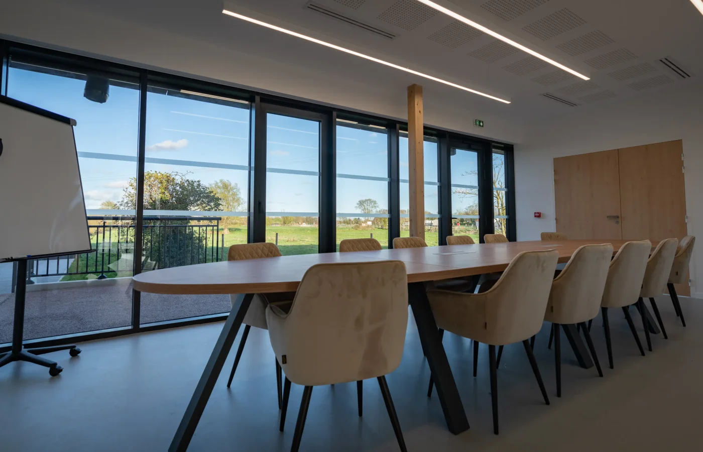Salle de réunion moderne avec baies vitrées panoramiques sur les paysages ruraux du Nord