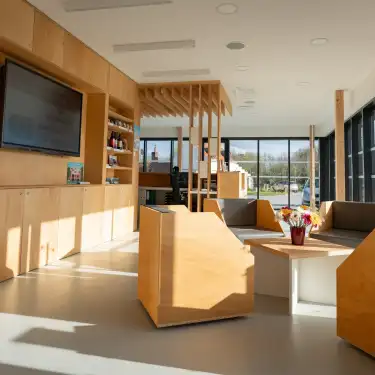 Intérieur moderne d'un centre d'accueil au port fluvial d'Aire-sur-la-Lys avec boiseries naturelles, mobilier contemporain et grandes baies vitrées