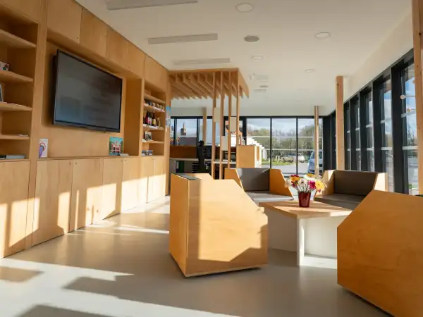Intérieur moderne d'un centre d'accueil au port fluvial d'Aire-sur-la-Lys avec boiseries naturelles, mobilier contemporain et grandes baies vitrées
