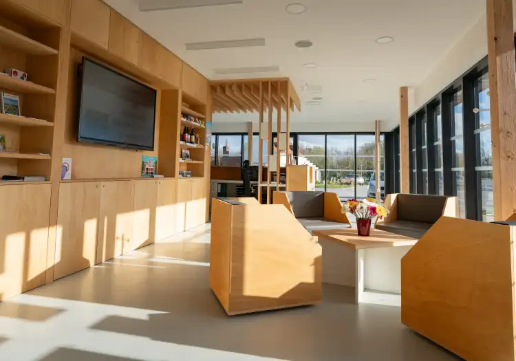 Intérieur moderne d'un centre d'accueil au port fluvial d'Aire-sur-la-Lys avec boiseries naturelles, mobilier contemporain et grandes baies vitrées