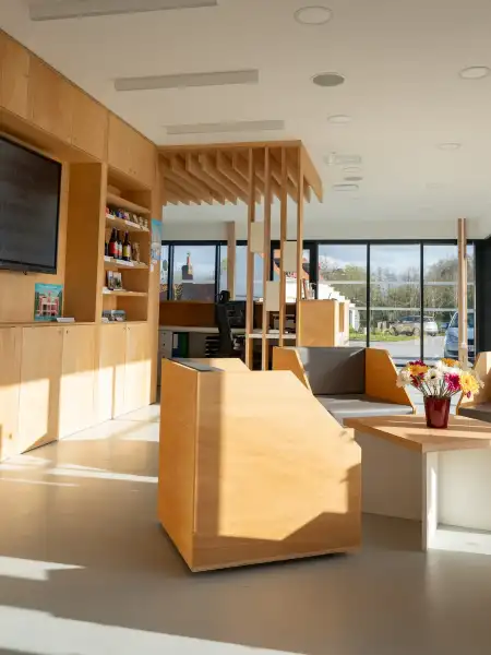 Intérieur moderne d'un centre d'accueil au port fluvial d'Aire-sur-la-Lys avec boiseries naturelles, mobilier contemporain et grandes baies vitrées