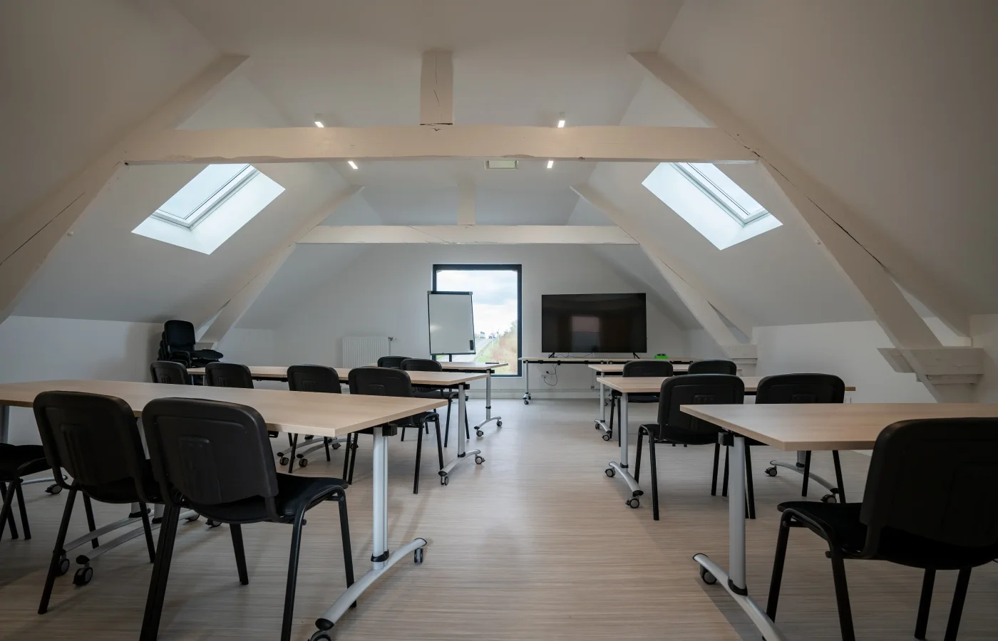 Salle de réunion moderne mansardée avec tables modulables et chaises noires